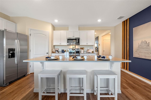 kitchen featuring white cabinetry, a breakfast bar area, an island with sink, and appliances with stainless steel finishes