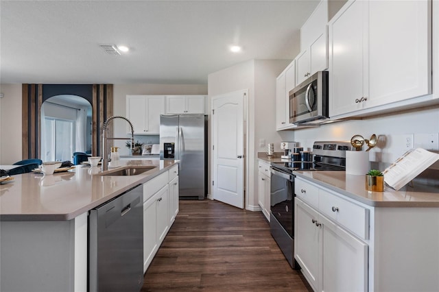 kitchen with sink, appliances with stainless steel finishes, white cabinetry, dark hardwood / wood-style floors, and an island with sink