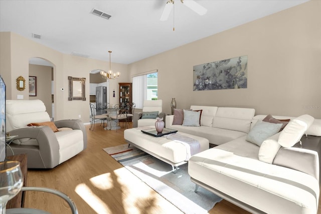 living room with ceiling fan with notable chandelier and light hardwood / wood-style flooring