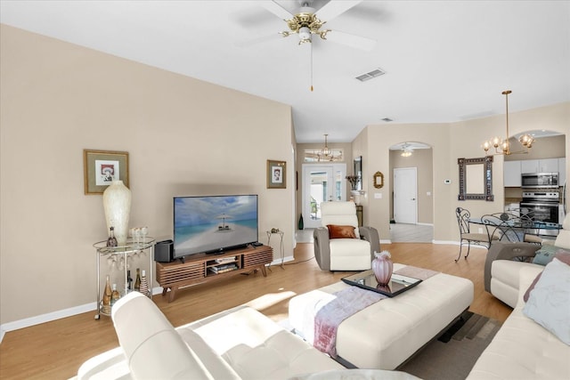 living room with hardwood / wood-style flooring and ceiling fan with notable chandelier