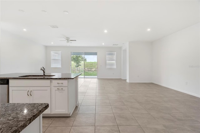 kitchen featuring white cabinetry, sink, dark stone counters, light tile patterned floors, and ceiling fan