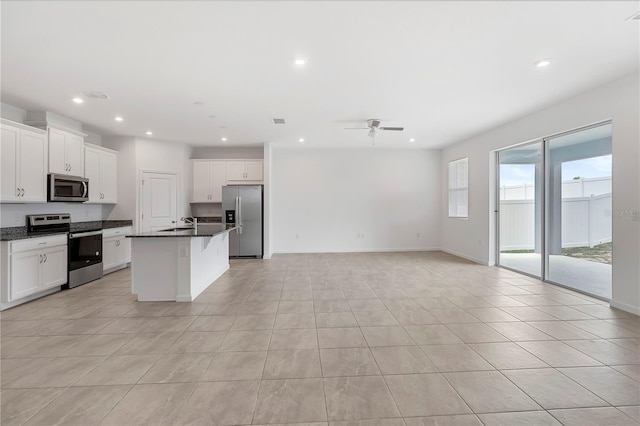 kitchen with light tile patterned flooring, white cabinetry, appliances with stainless steel finishes, and a kitchen island with sink