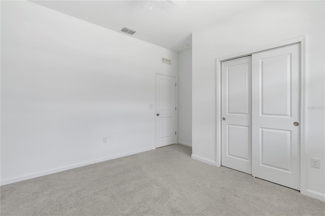 unfurnished bedroom with light carpet, ceiling fan, and a closet