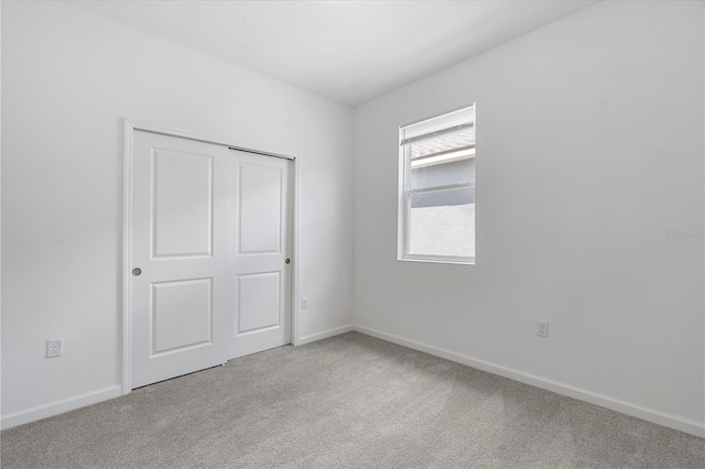 unfurnished bedroom with light carpet and a closet