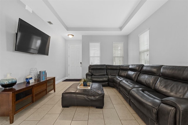 living room featuring light tile patterned floors and a tray ceiling