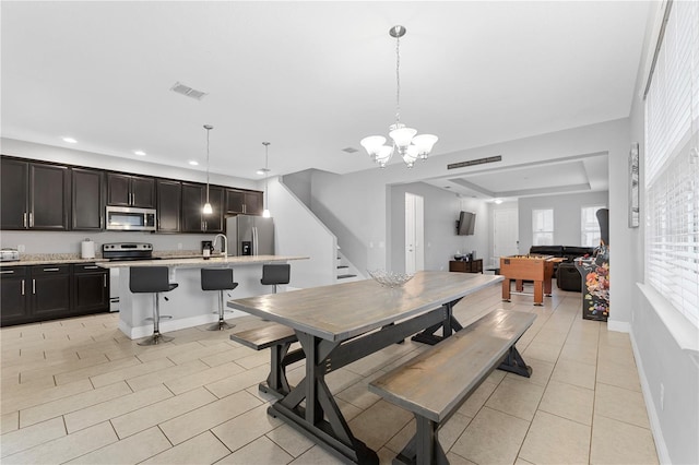 dining area featuring a notable chandelier, sink, and a raised ceiling