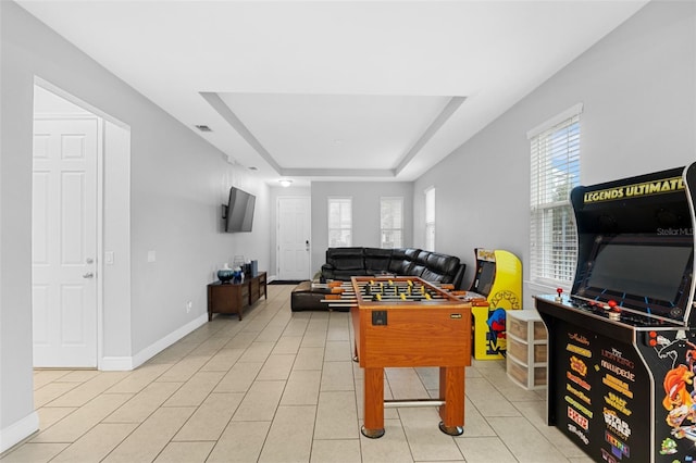 game room featuring a raised ceiling and light tile patterned floors