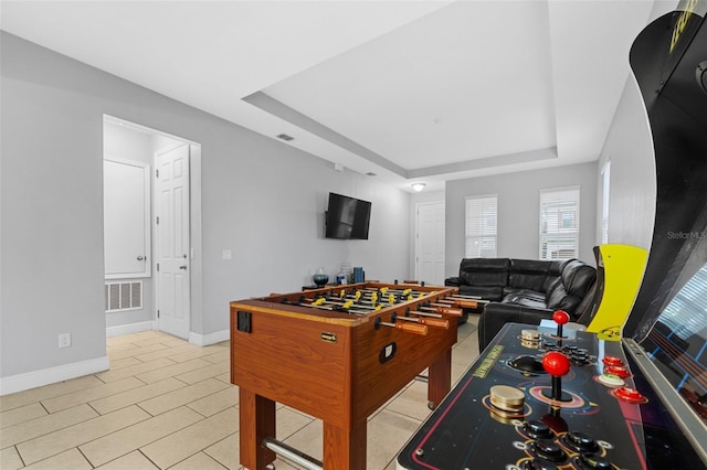 recreation room featuring a raised ceiling and light tile patterned floors