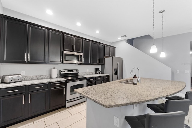 kitchen with decorative light fixtures, sink, a kitchen breakfast bar, a kitchen island with sink, and stainless steel appliances