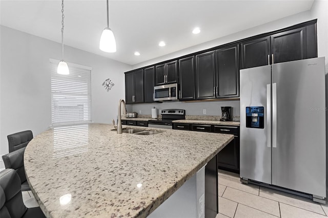 kitchen featuring appliances with stainless steel finishes, decorative light fixtures, sink, a breakfast bar area, and a center island with sink