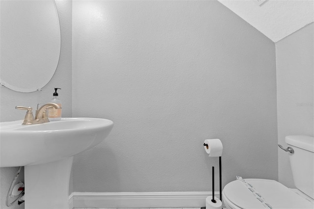 bathroom with lofted ceiling, toilet, and sink