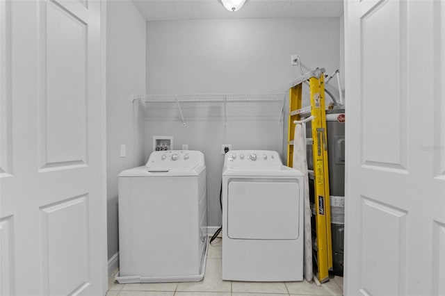 washroom featuring light tile patterned flooring, washing machine and clothes dryer, electric water heater, and a textured ceiling