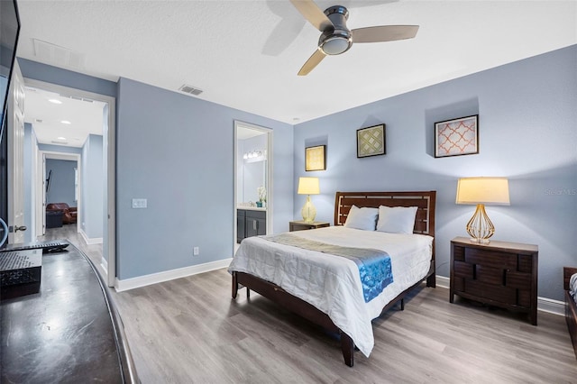 bedroom featuring ensuite bath, light hardwood / wood-style flooring, a textured ceiling, and ceiling fan