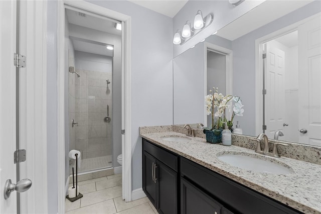 bathroom featuring tile patterned flooring, vanity, toilet, and a shower with shower door