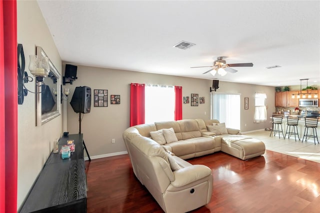 living room with a wealth of natural light, dark hardwood / wood-style floors, and ceiling fan