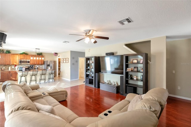 living room with ceiling fan, light hardwood / wood-style floors, and a textured ceiling