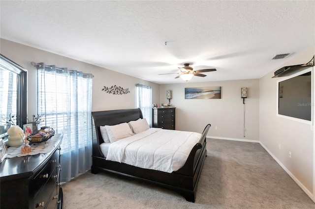 carpeted bedroom with ceiling fan and a textured ceiling