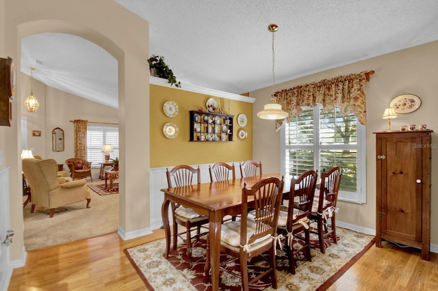 dining area featuring hardwood / wood-style flooring, vaulted ceiling, and a textured ceiling