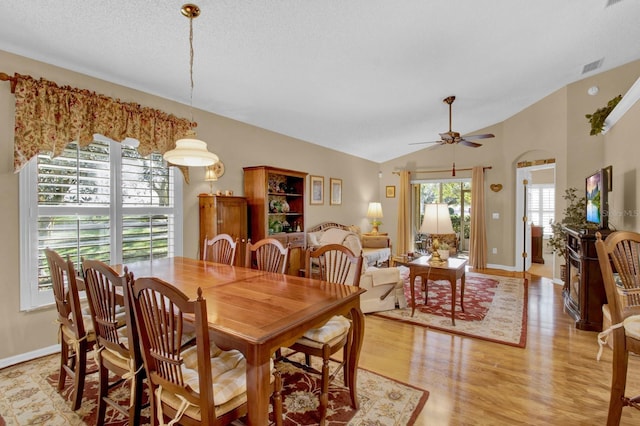 dining room with ceiling fan, lofted ceiling, a textured ceiling, and light wood-type flooring