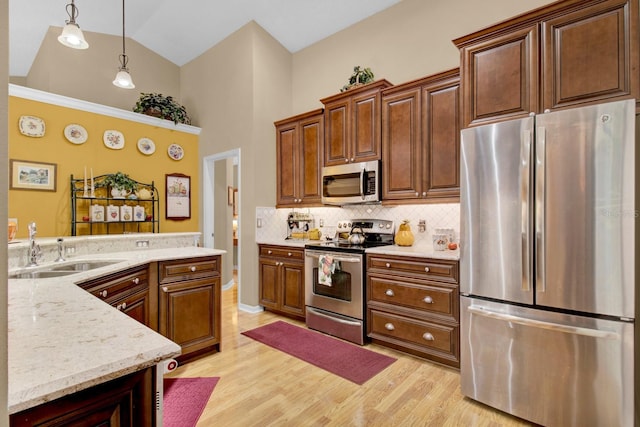 kitchen with pendant lighting, sink, decorative backsplash, light hardwood / wood-style floors, and stainless steel appliances