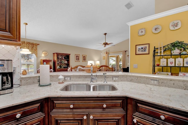 kitchen featuring pendant lighting, a wealth of natural light, light stone countertops, and ceiling fan