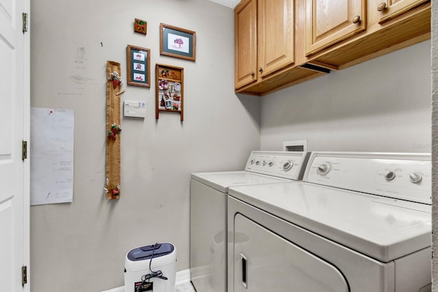 washroom with cabinets and washing machine and clothes dryer