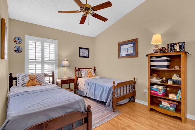 bedroom with ceiling fan, lofted ceiling, a textured ceiling, and light wood-type flooring