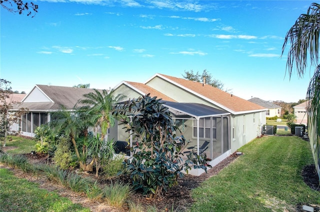 rear view of property featuring central AC, a yard, and glass enclosure