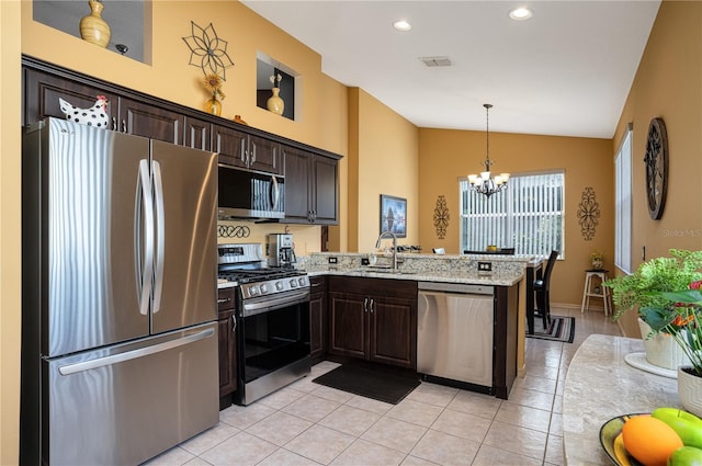 kitchen with vaulted ceiling, sink, light tile patterned floors, kitchen peninsula, and stainless steel appliances