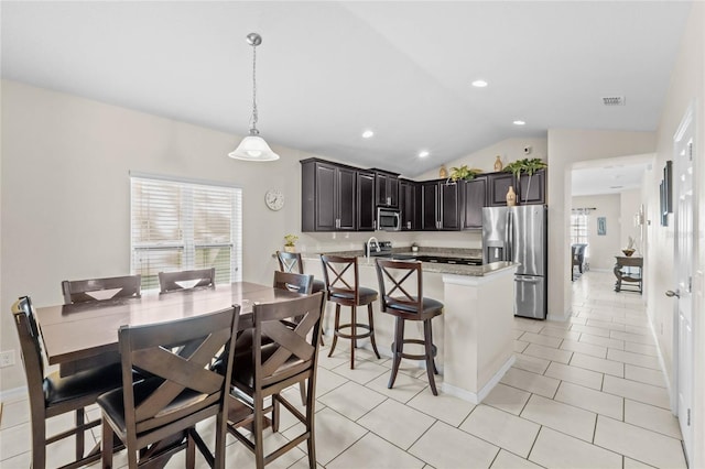 kitchen with lofted ceiling, light tile patterned floors, hanging light fixtures, and appliances with stainless steel finishes