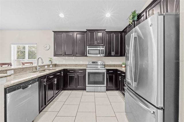 kitchen with sink, light tile patterned floors, light stone countertops, and appliances with stainless steel finishes