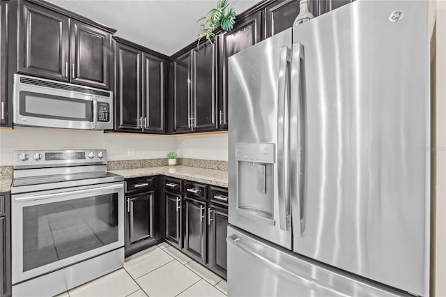 kitchen featuring light tile patterned flooring, appliances with stainless steel finishes, and light stone counters