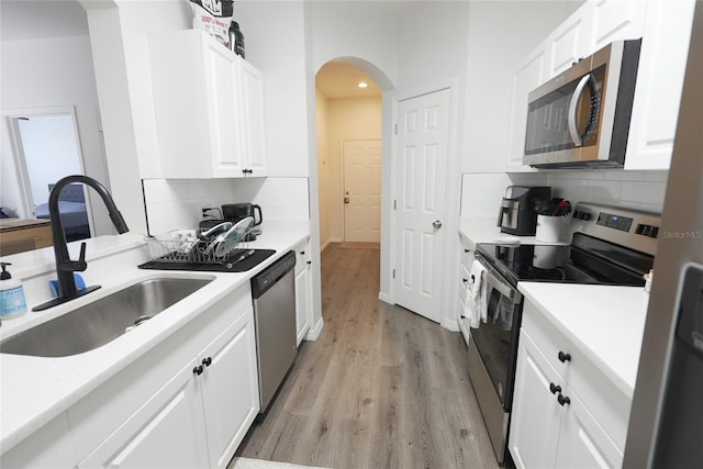 kitchen with appliances with stainless steel finishes, sink, decorative backsplash, and white cabinets