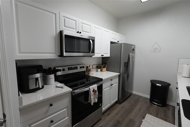 kitchen with dark wood-type flooring, stainless steel appliances, decorative backsplash, and white cabinets