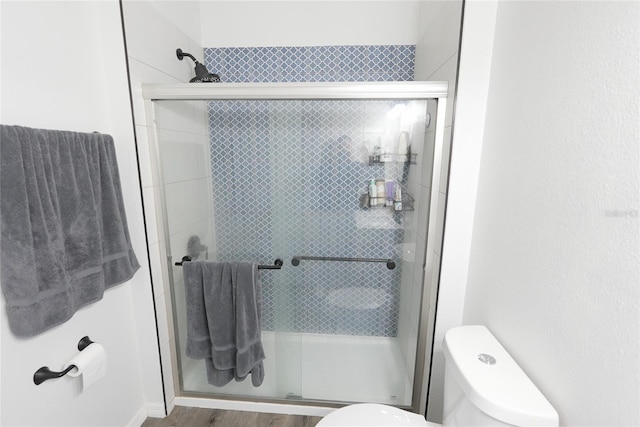 bathroom featuring hardwood / wood-style flooring, toilet, and a shower with shower door