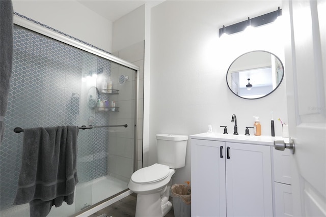 bathroom featuring hardwood / wood-style flooring, vanity, a shower with shower door, and toilet