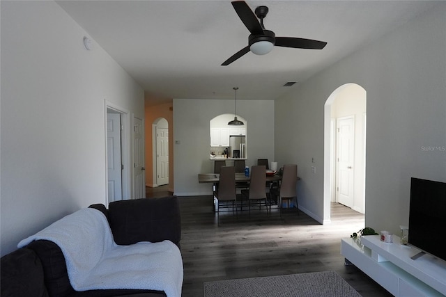 living room with dark wood-type flooring and ceiling fan