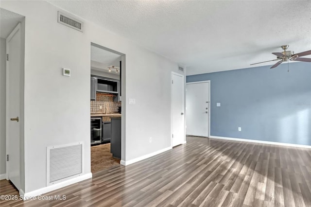 unfurnished living room with ceiling fan, dark wood-type flooring, and a textured ceiling