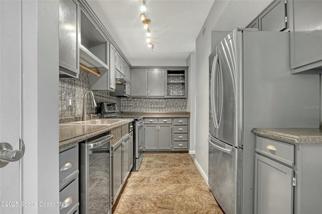 kitchen featuring sink, decorative backsplash, gray cabinets, and appliances with stainless steel finishes