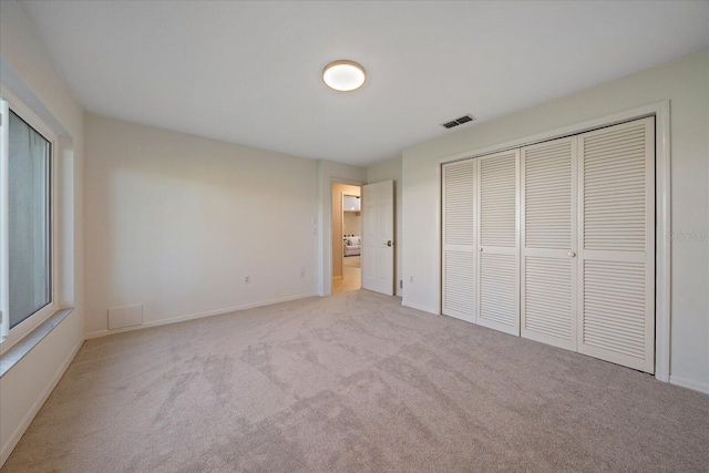 unfurnished bedroom featuring light colored carpet and a closet