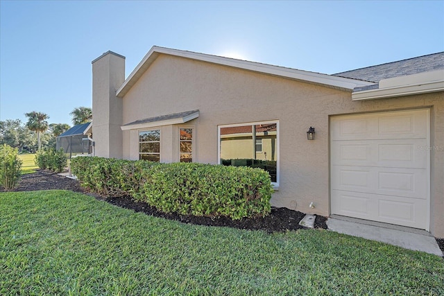 view of home's exterior with a garage, glass enclosure, and a lawn