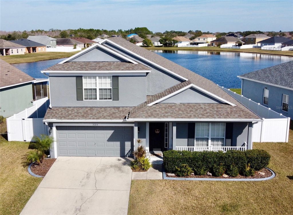 view of front of property with a garage, a front yard, and a water view