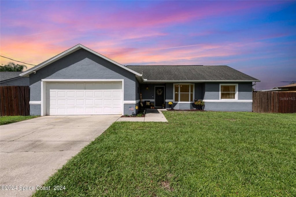 ranch-style home featuring a garage and a lawn