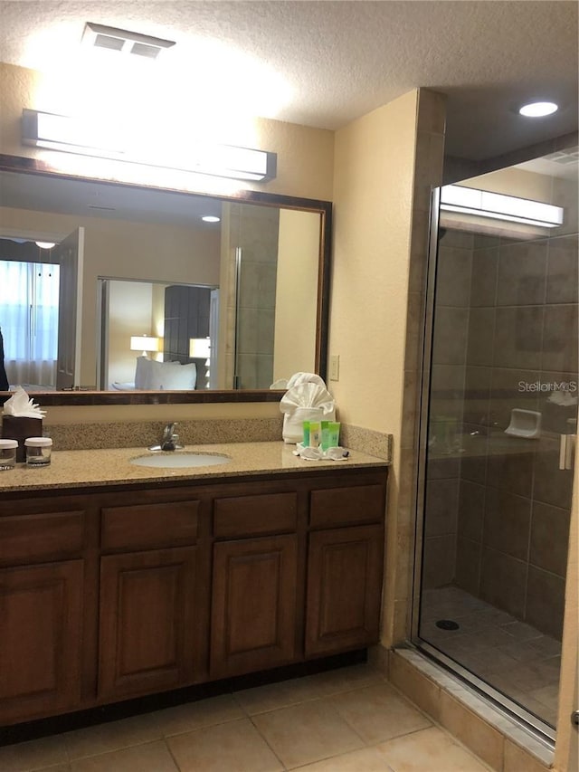 bathroom with tile patterned flooring, vanity, a shower with door, and a textured ceiling