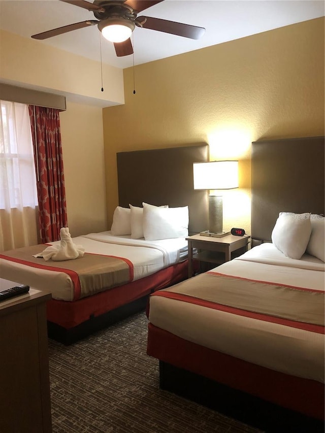 bedroom with ceiling fan and dark colored carpet