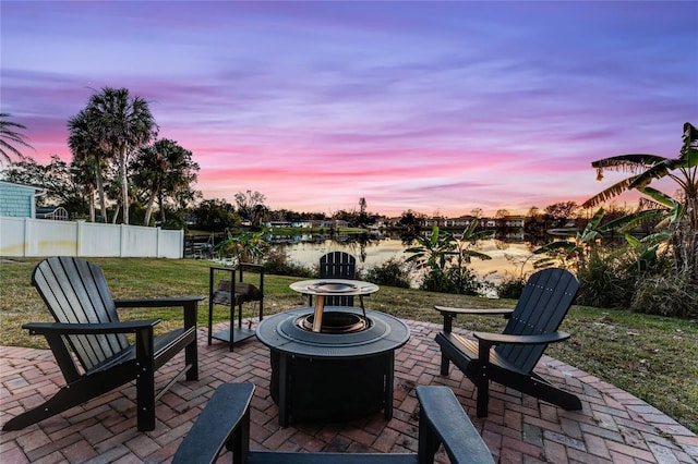 patio terrace at dusk with a water view and an outdoor fire pit