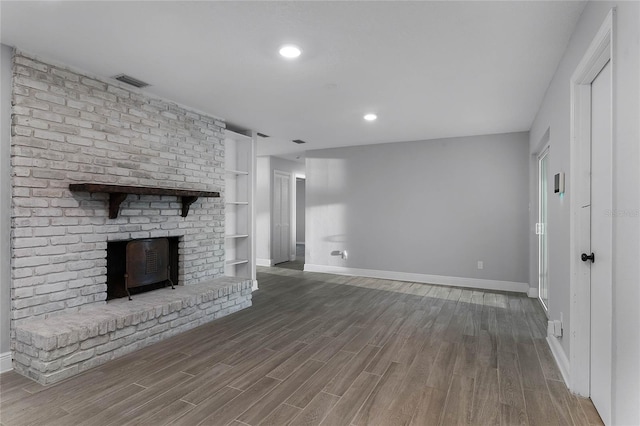 unfurnished living room featuring hardwood / wood-style flooring, a fireplace, and built in shelves