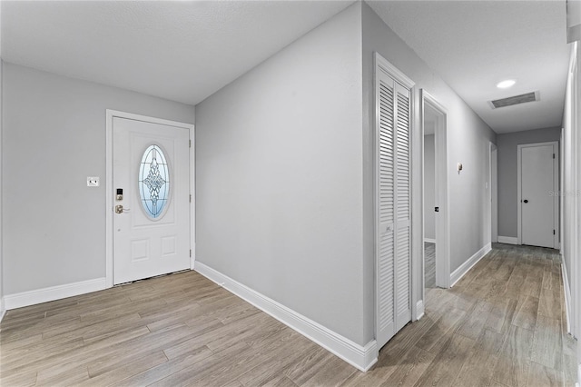 foyer entrance featuring a textured ceiling and light hardwood / wood-style flooring