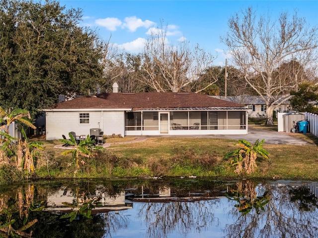 back of property with a yard, a sunroom, and a water view