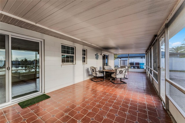 unfurnished sunroom with a water view and wooden ceiling